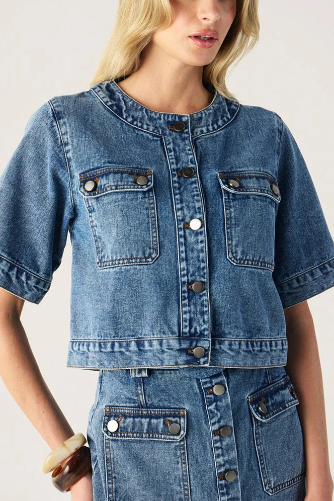 Woman wearing a blue denim jacket on a plain background