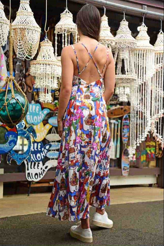 Woman in a colorful dress standing in front of decorative lights and signs.