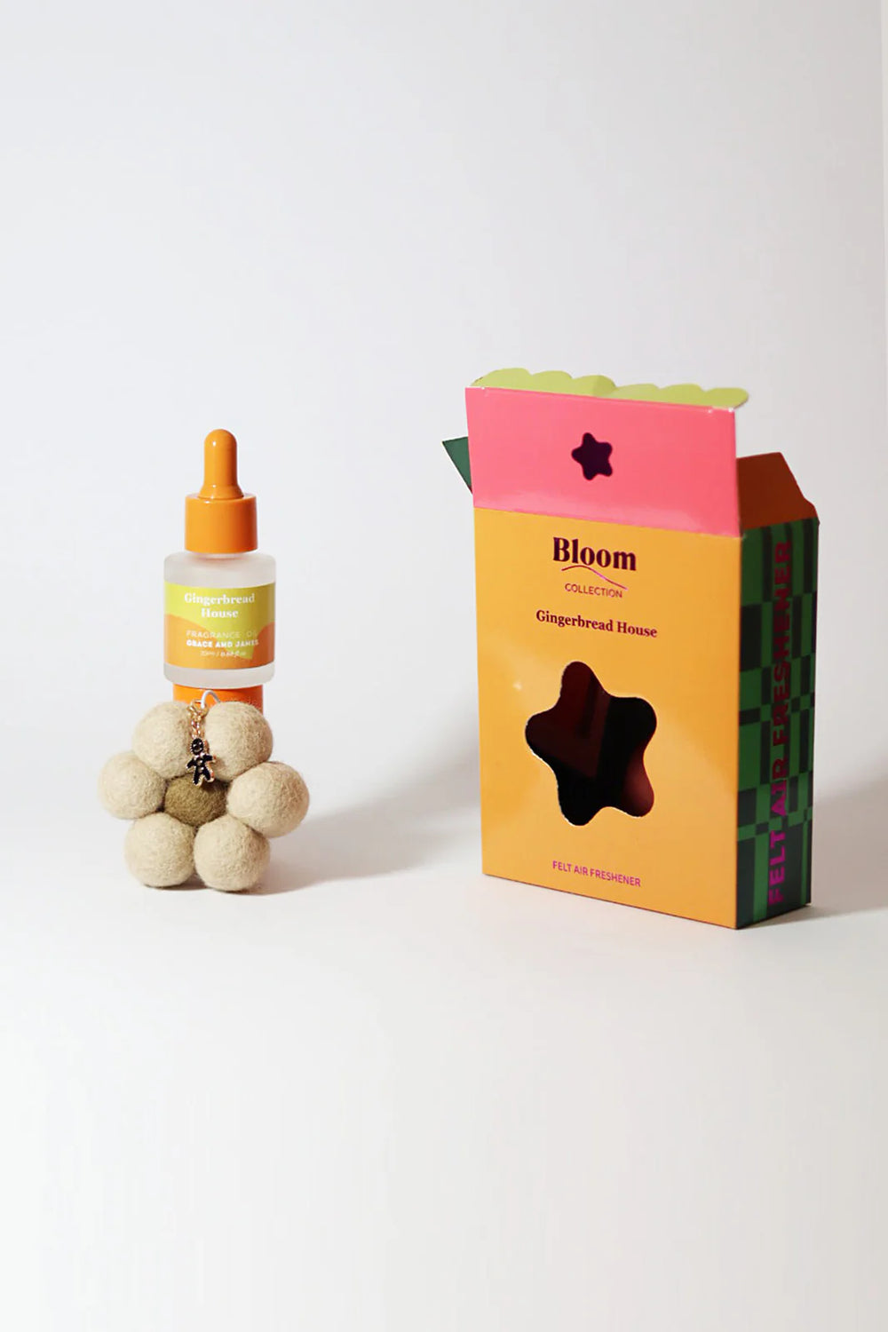 Fragranced oil bottle with dropper, flower shaped felt air freshener, and box labeled 'Bloom' on a white background