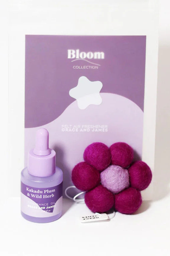 Bloom product set with a fragranced oil bottle and fuchsia flower shaped felt air freshener on a white background