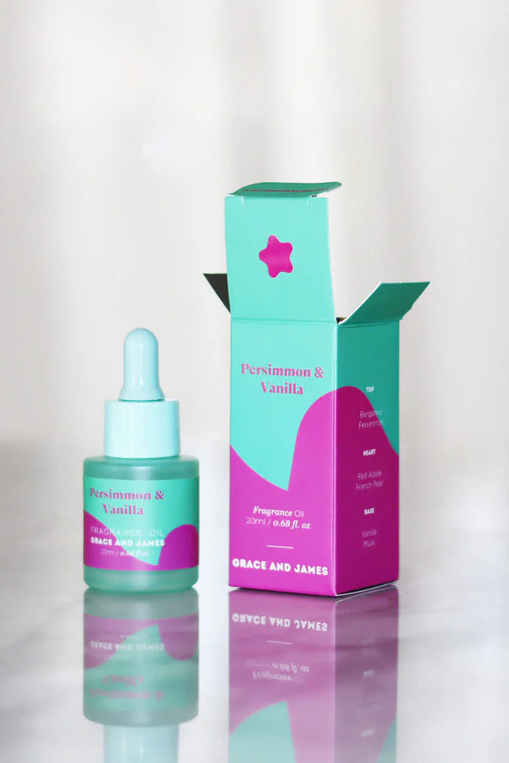 Bottle and box of Persimmon & Vanilla face oil on a reflective surface with a blurred background