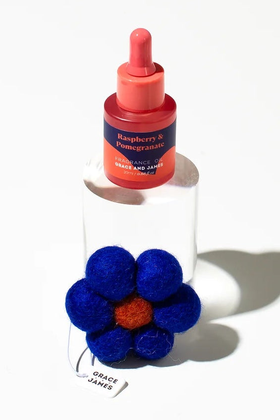 Bottle fragranced oil with a blue flower-shaped felt air freshener on a white background