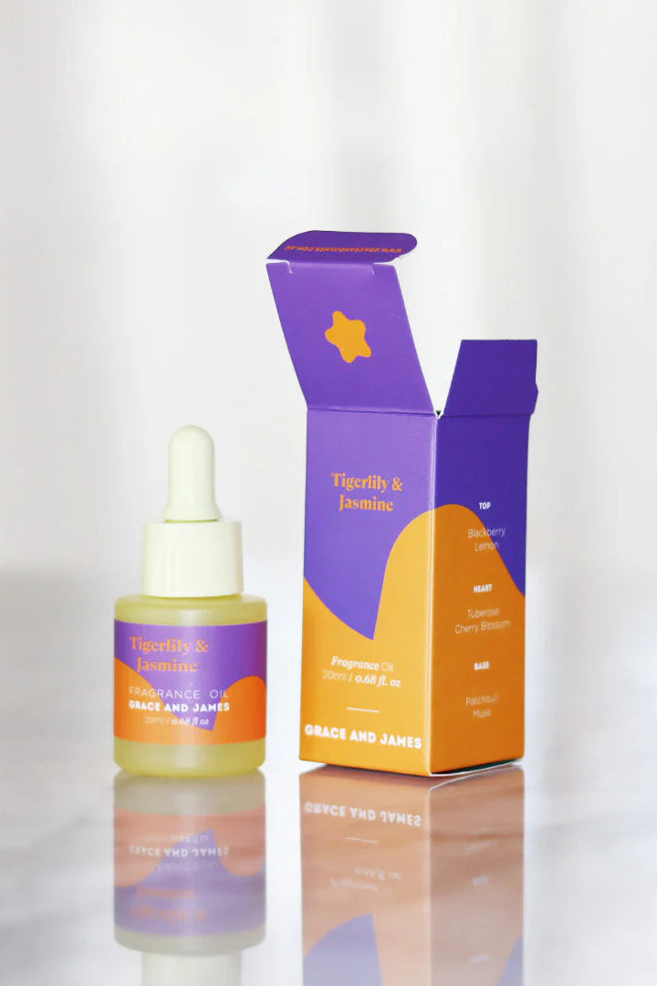 Fragranced oil dropper bottle with its packaging on a reflective surface