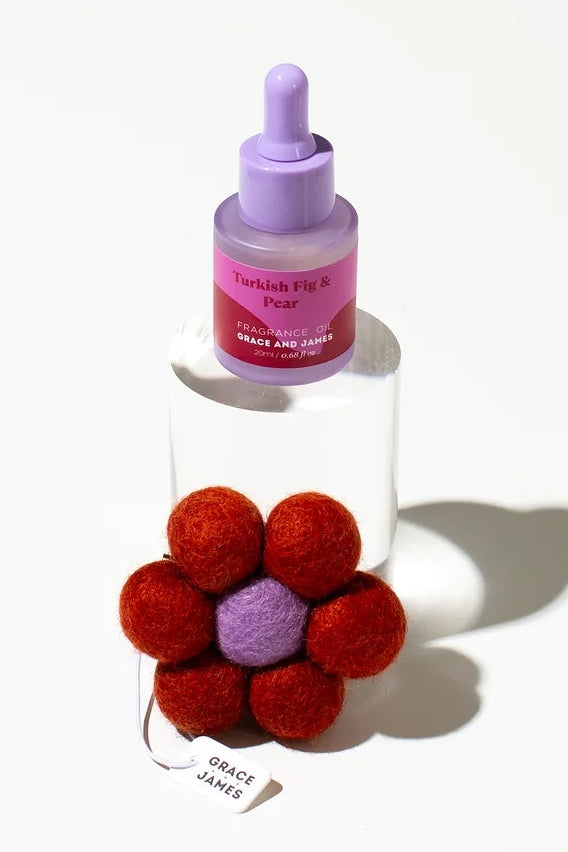 Small fragranced oil bottle with a dropper and a red flower-shaped felt air freshener on a white background