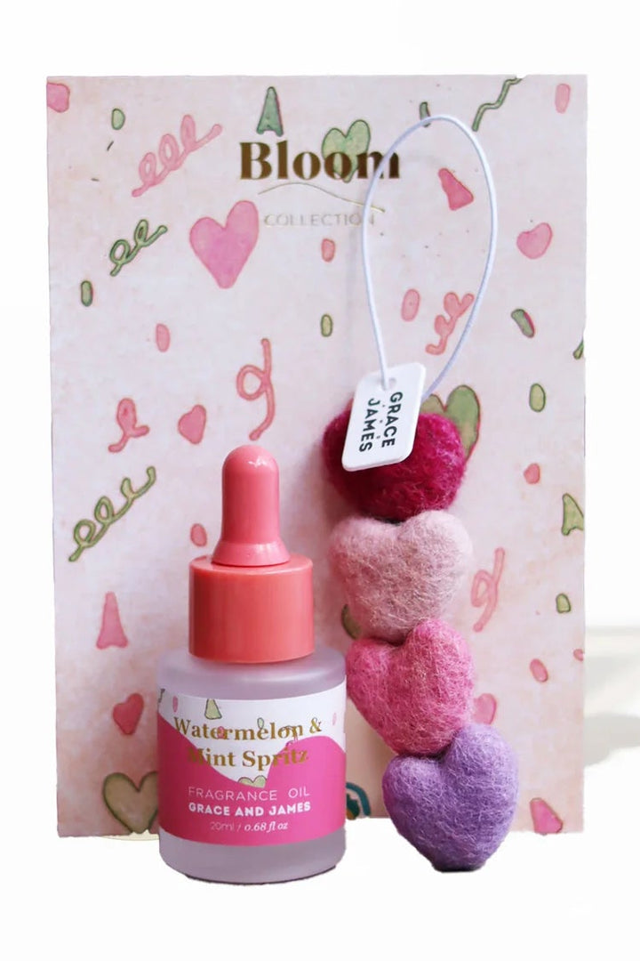 Bottle of watermelon scent oil with a decorative heart-shaped packaging on a white background