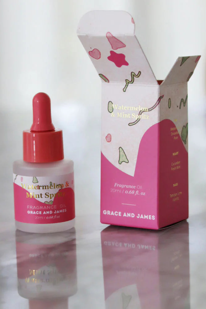 Grace and James fragranced oil bottle and packaging on a reflective surface with a blurred background