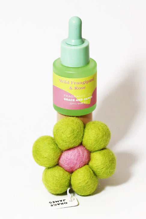 Colorful bottle of fragranced oil and flower-shaped felt air freshener on a white background