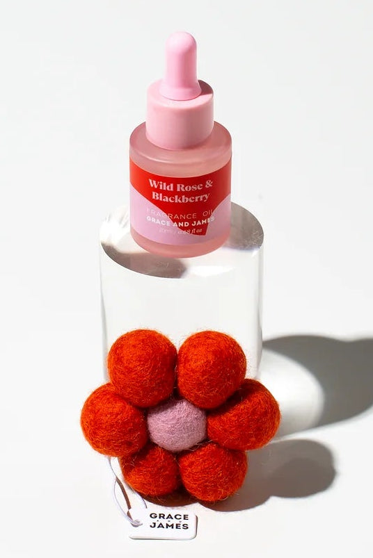 Frangranced oil bottle with a red flower shaped felt air freshener on a white background