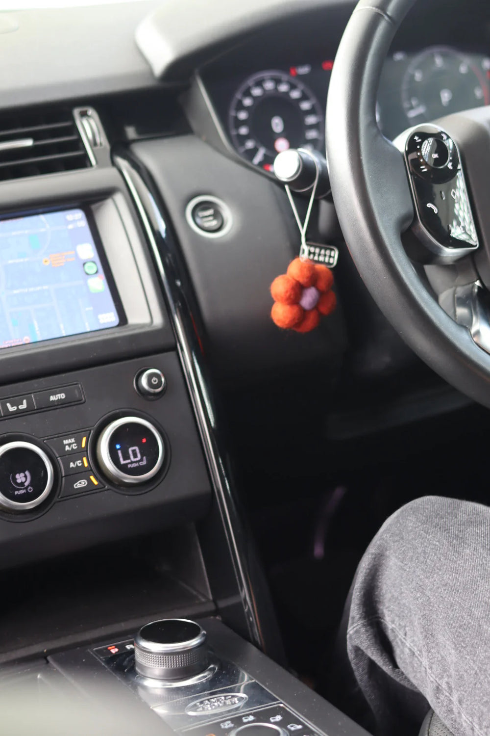 Car interior with a dashboard, steering wheel, and flower shaped felt air freshener