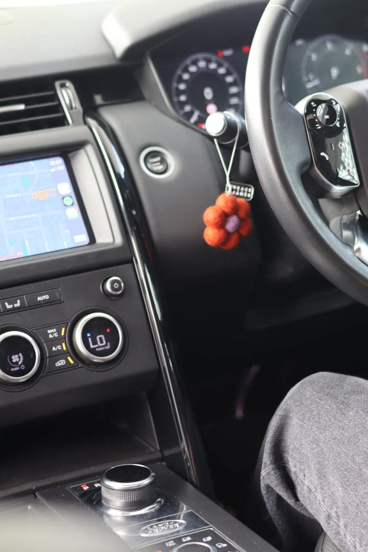 Car interior with a dashboard, steering wheel, and flower shaped felt air freshener