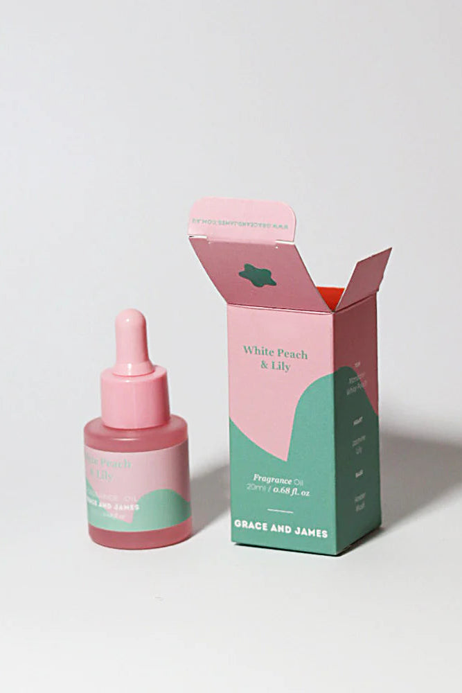 Pink and green fragranced oil bottle and box of Grace and James product on a white background