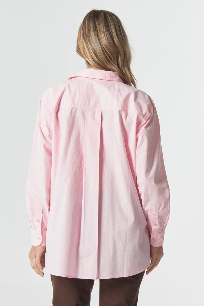 Person wearing a pink shirt and brown pants on a white background