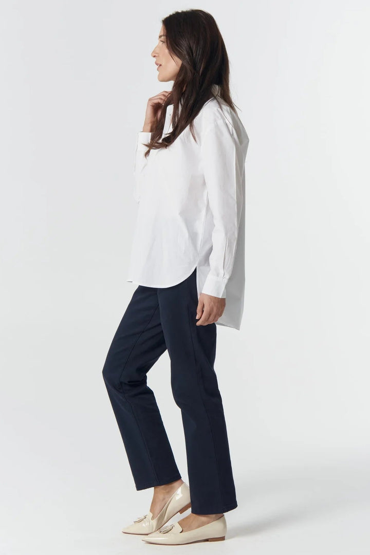 Woman wearing a white shirt and navy pants on a white background