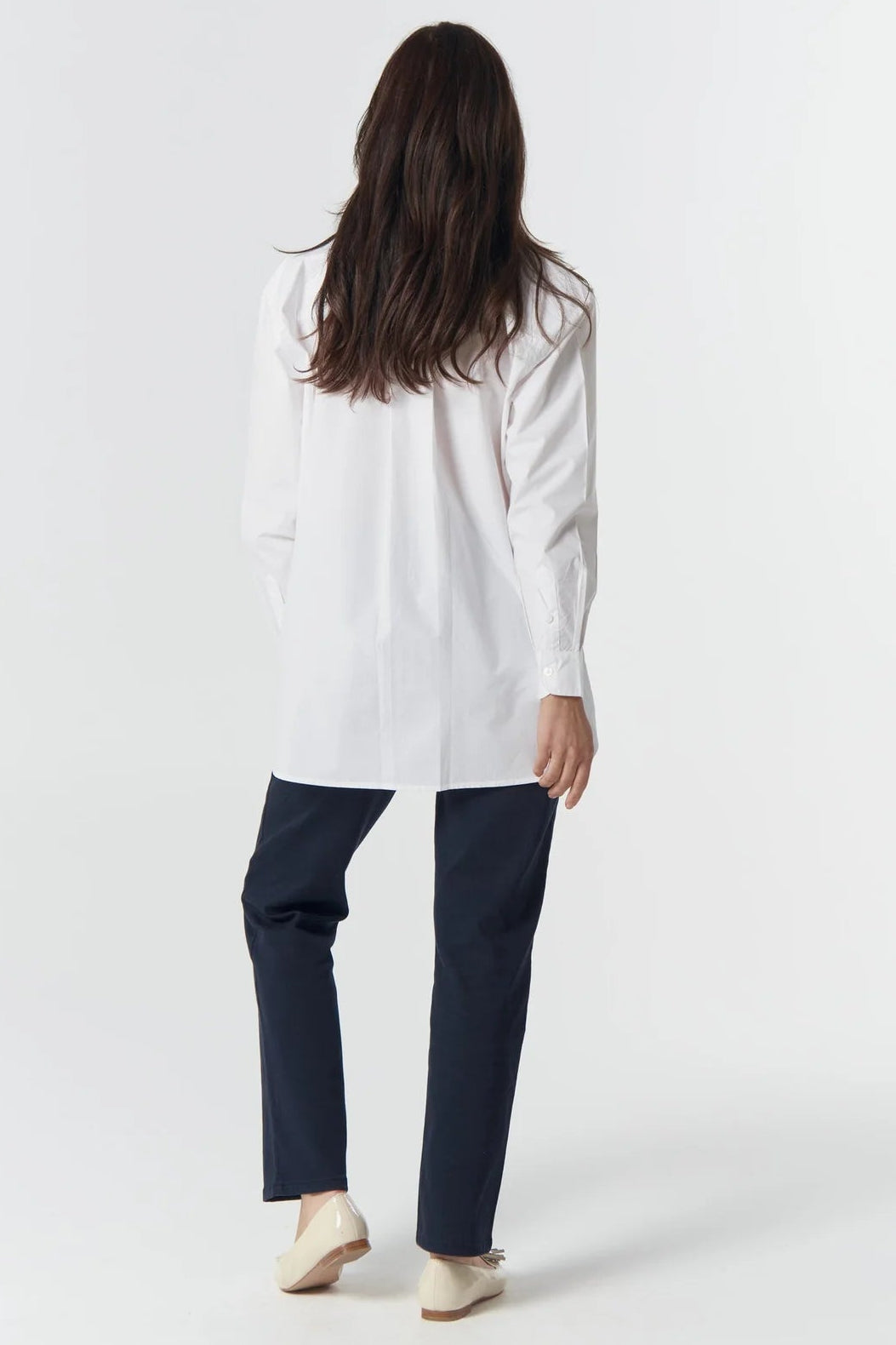 Person wearing a white shirt and navy pants on a white background