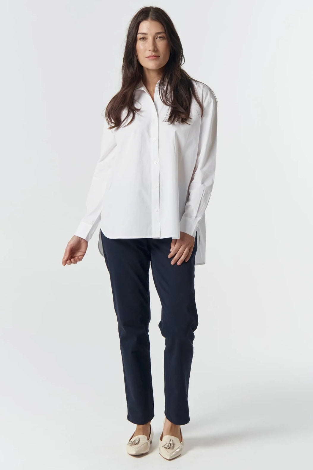 Woman wearing a white blouse and navy pants on a white background