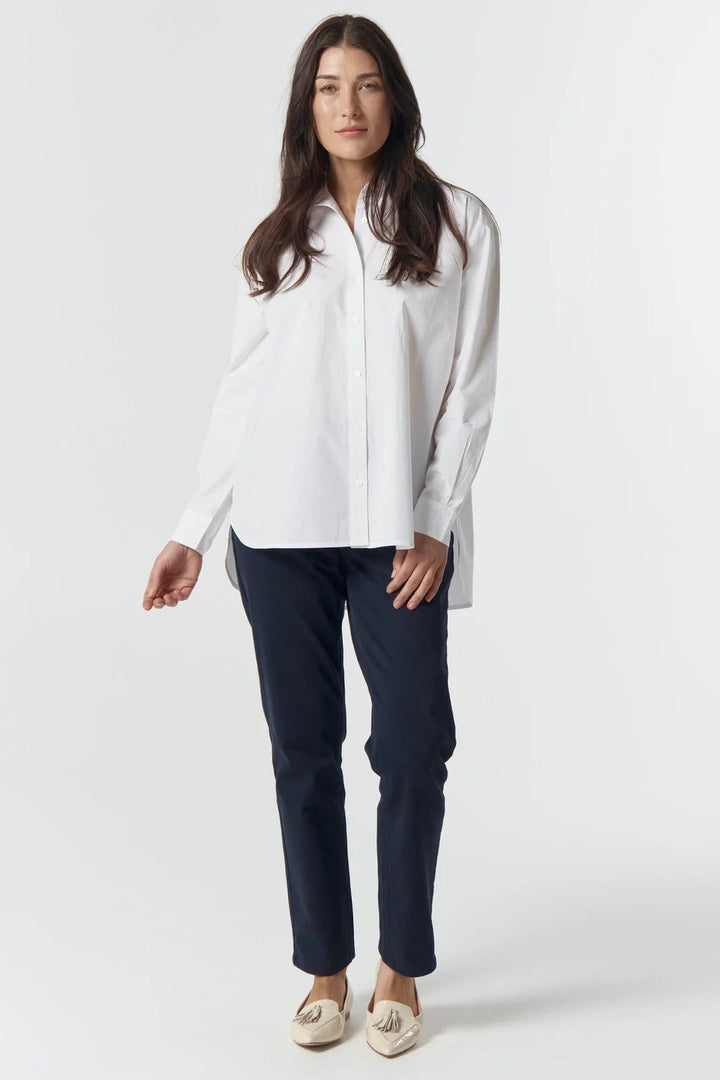 Woman wearing a white blouse and navy pants on a white background