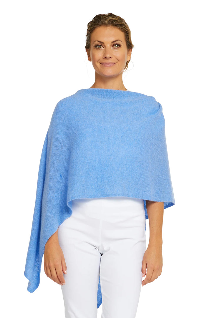 A woman wearing a blue cashmere topper and white pants.