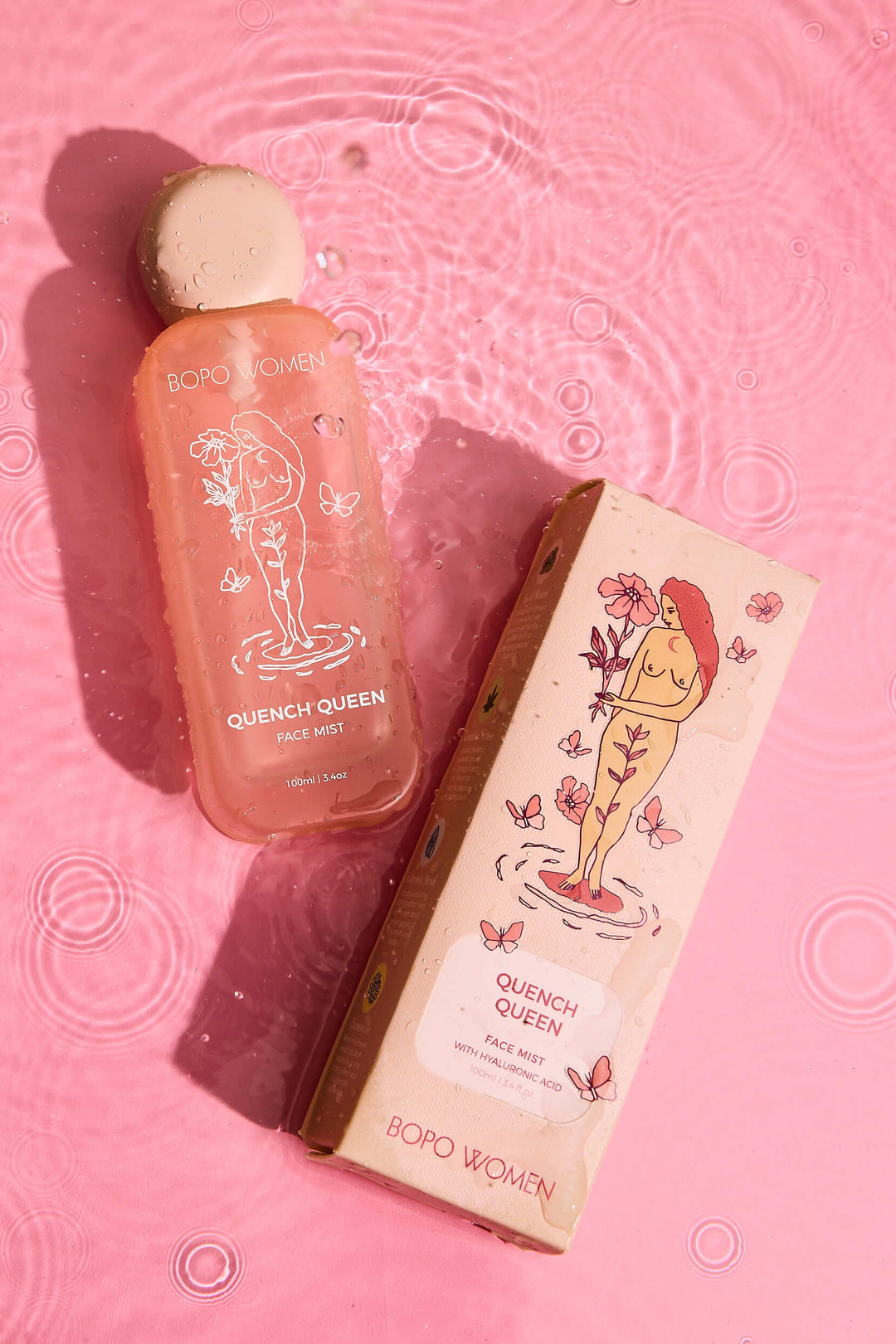 A bottle of Quench Queen Face Mist with a beige cap, next to its packaging box with floral illustrations, placed on a pink bubbly background.