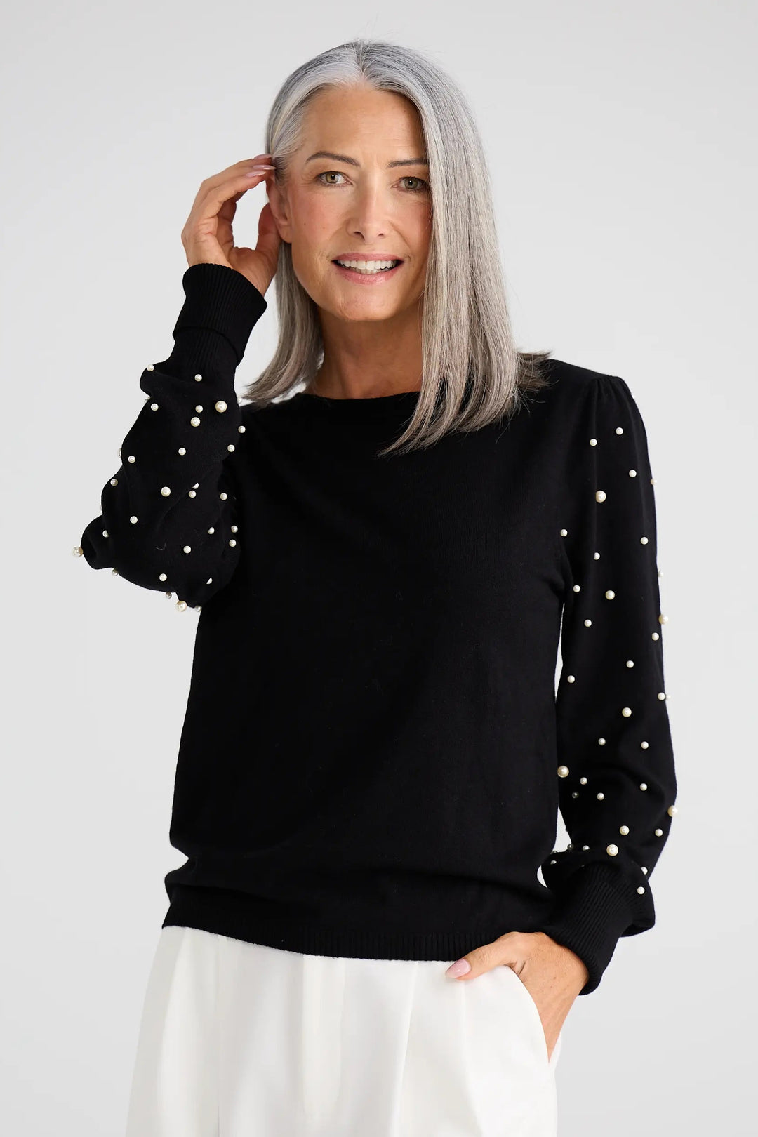 Woman wearing a black sweater with white polka dots on a white background