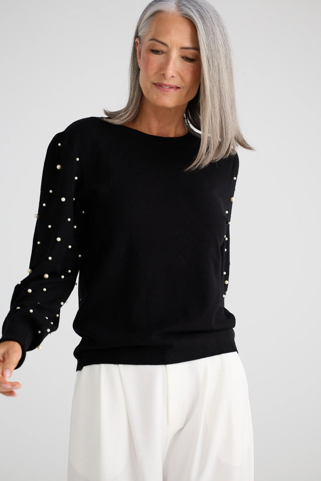 Woman wearing a black sweater with white polka dots on a plain background