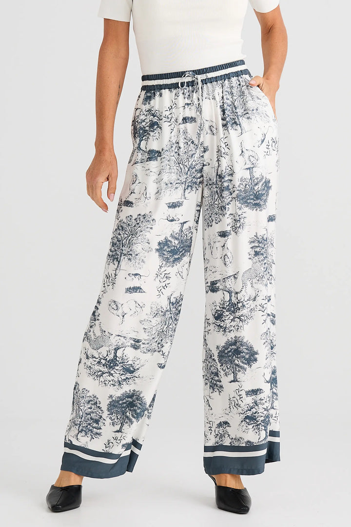 Woman wearing white blouse and wide-leg pants with blue floral pattern on a white background