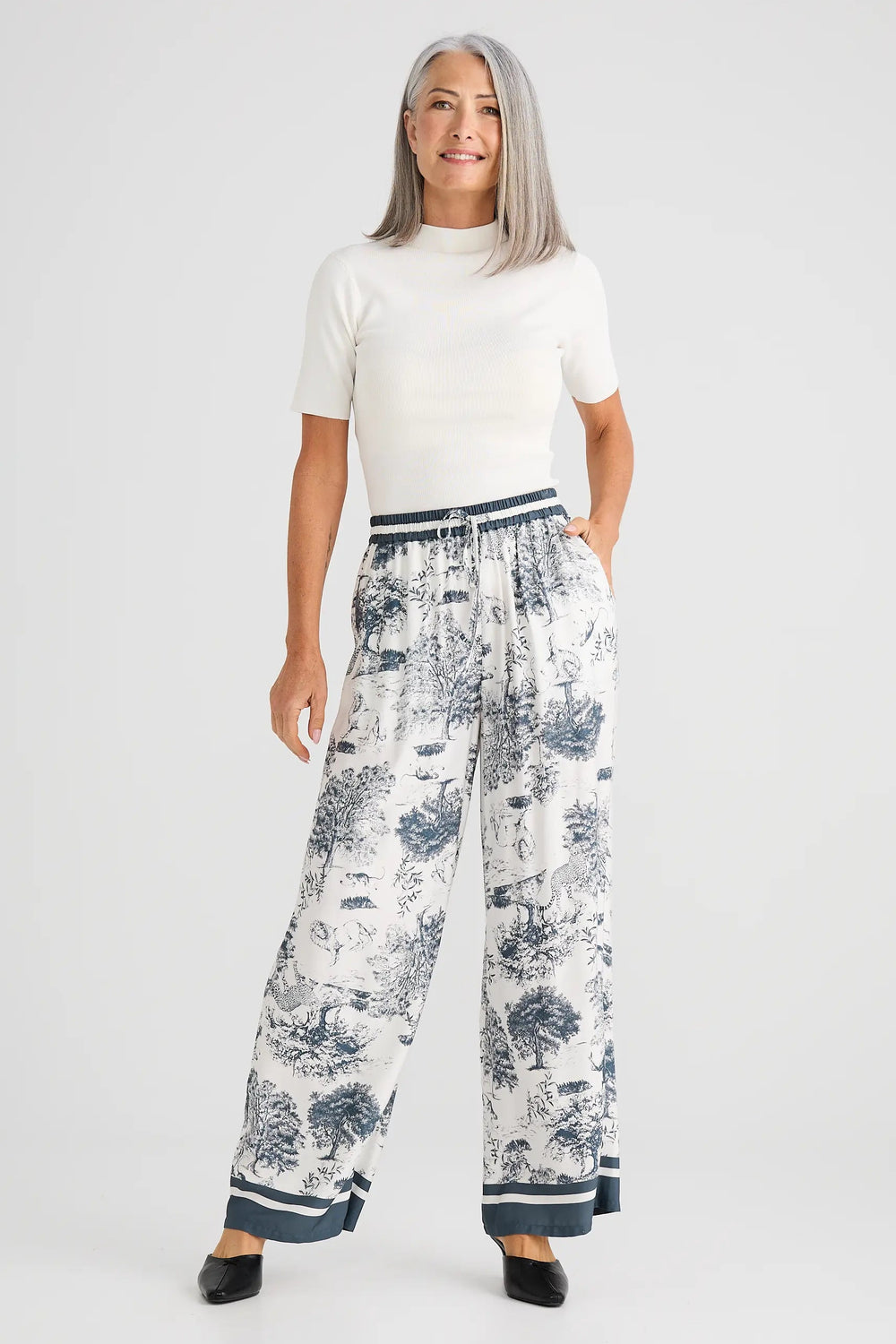 Woman wearing a white top and floral pants on a white background