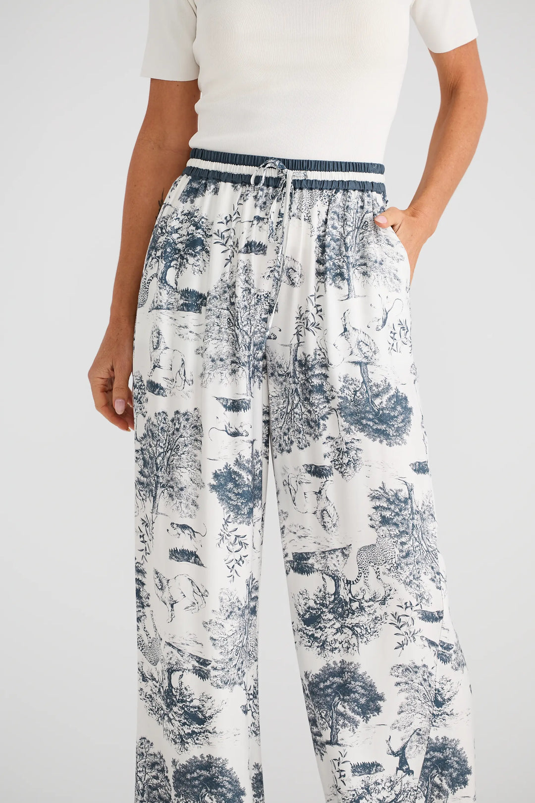 Person wearing a white top and patterned pants on a plain background