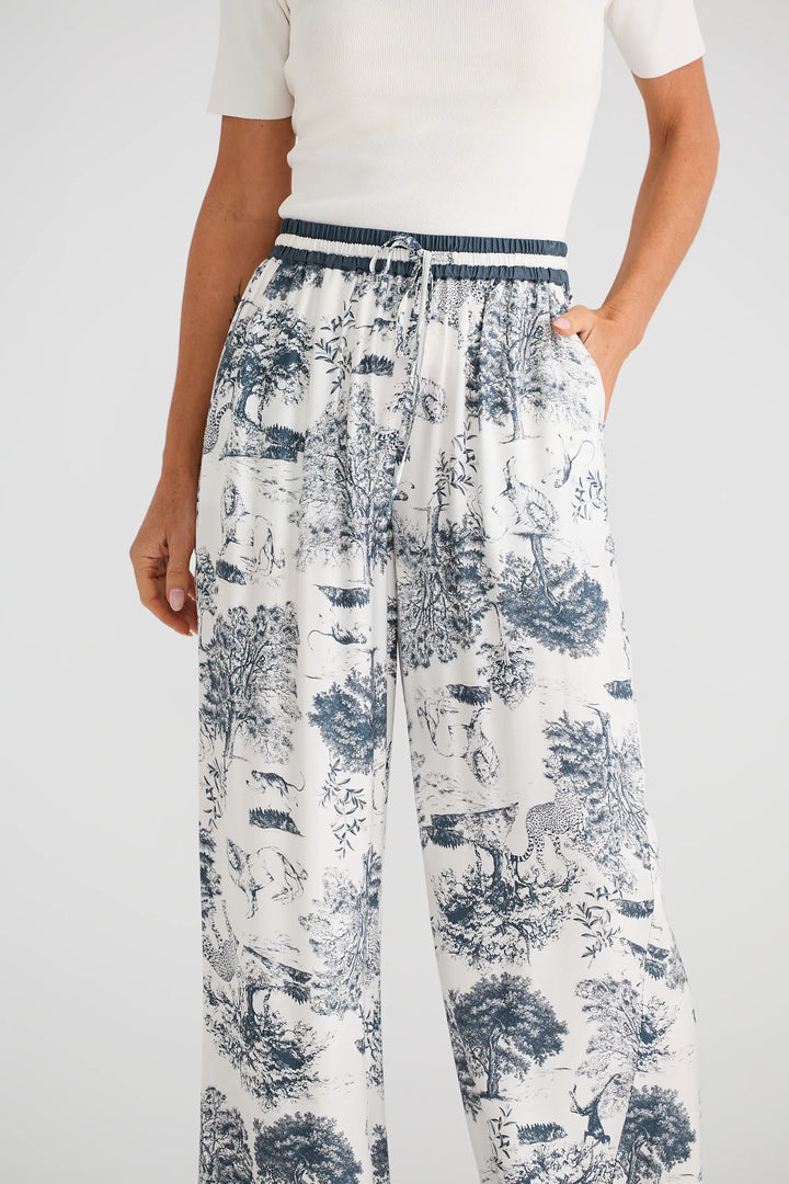 Person wearing a white top and patterned pants on a plain background