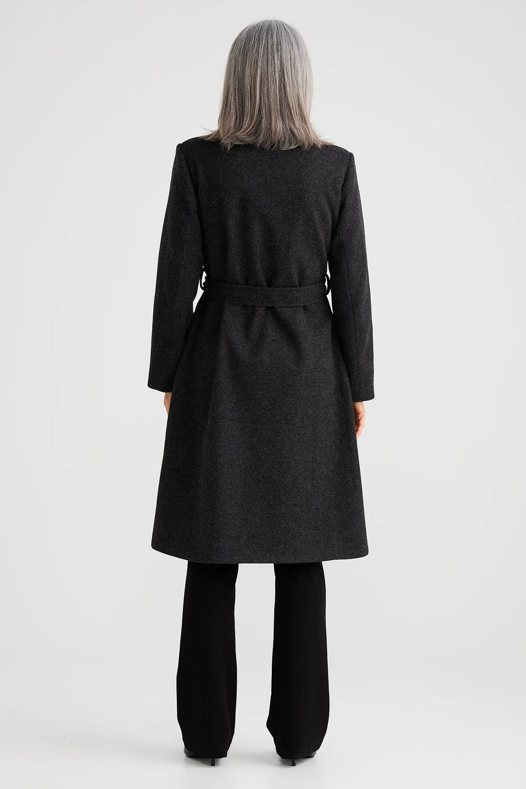 Person wearing a long dark coat on a white background