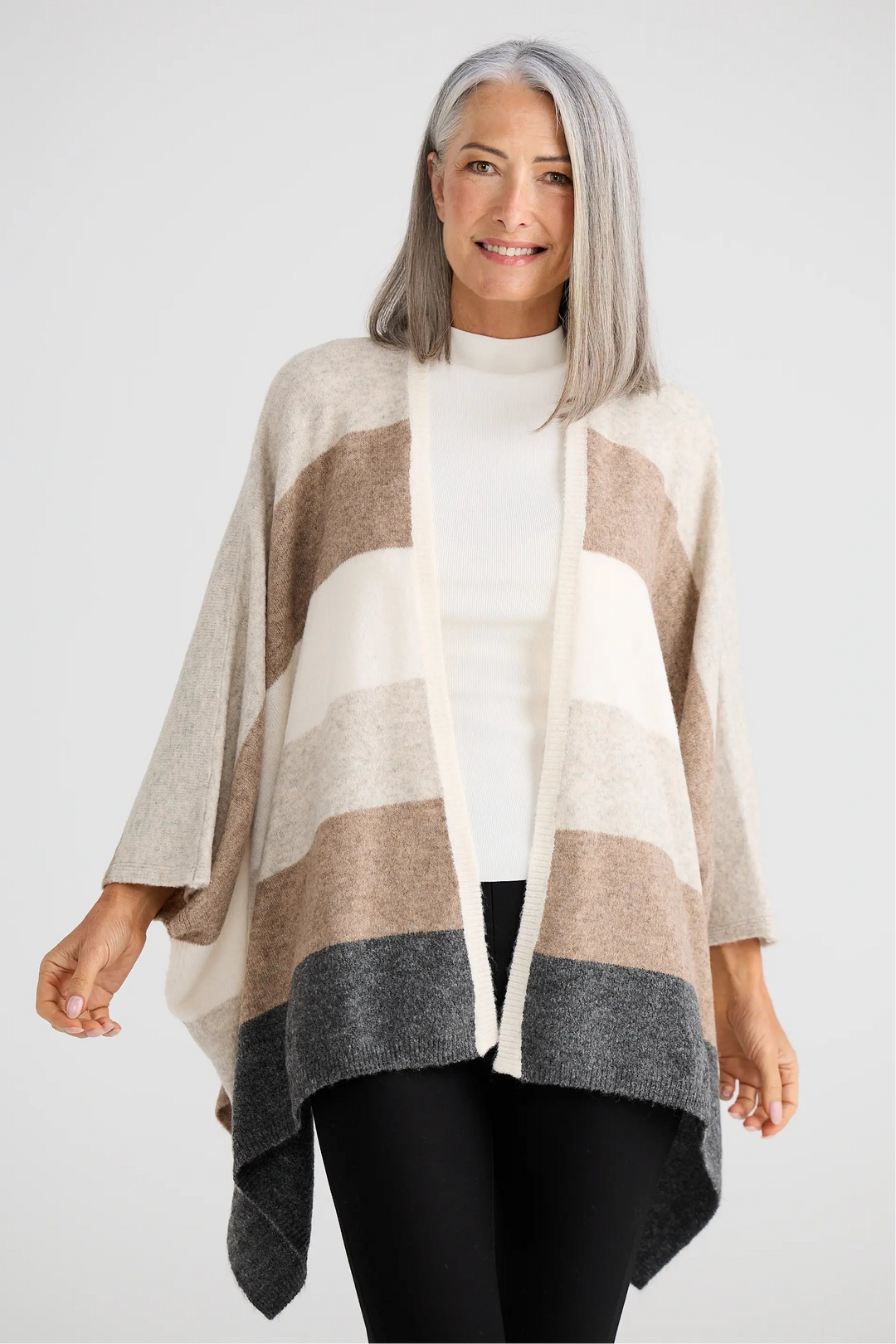 Woman wearing a striped poncho with a plain background