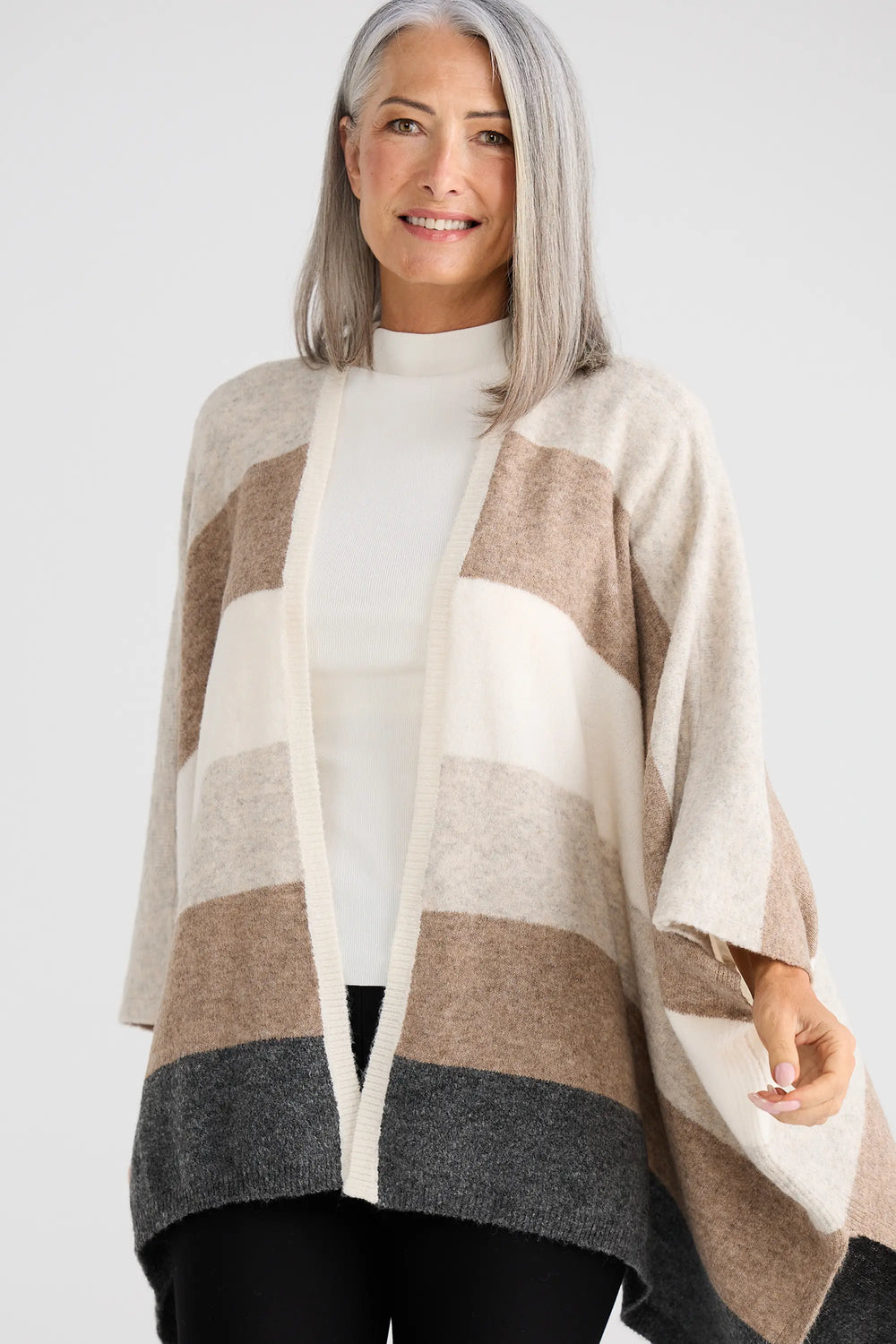 Woman wearing a striped poncho with a plain background