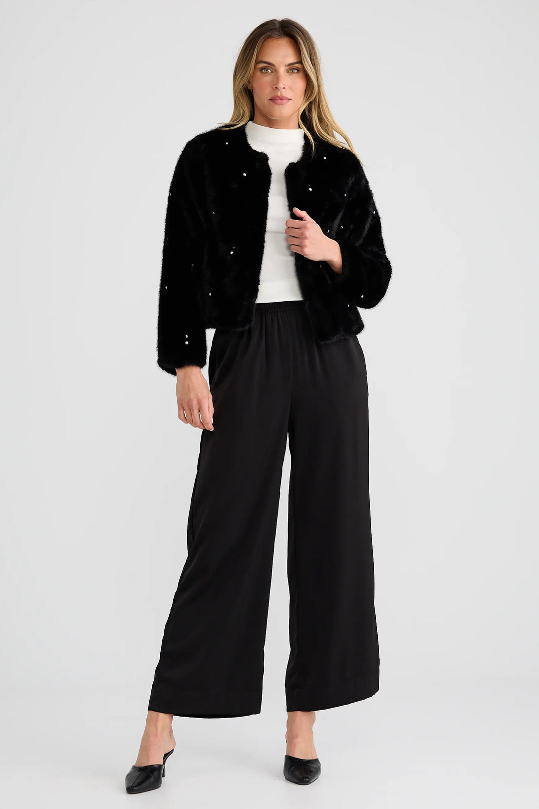 Woman wearing a black jacket and black pants on a white background