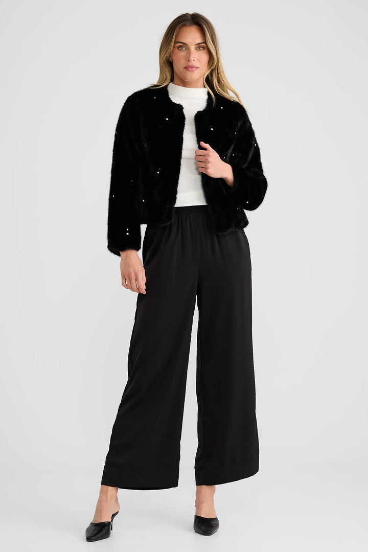 Woman wearing a black jacket and black pants on a white background