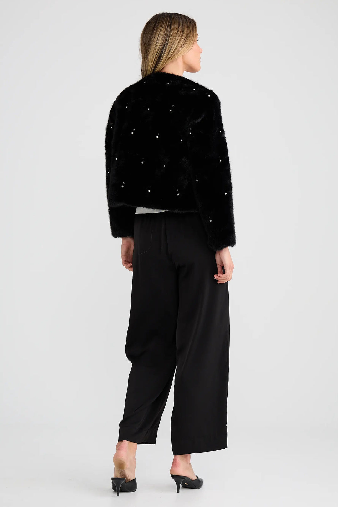 Woman wearing a black outfit with sparkling embellishments on a white background