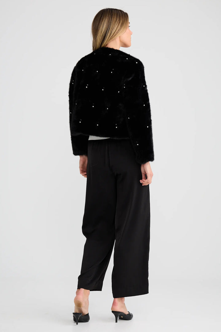 Woman wearing a black outfit with sparkling embellishments on a white background