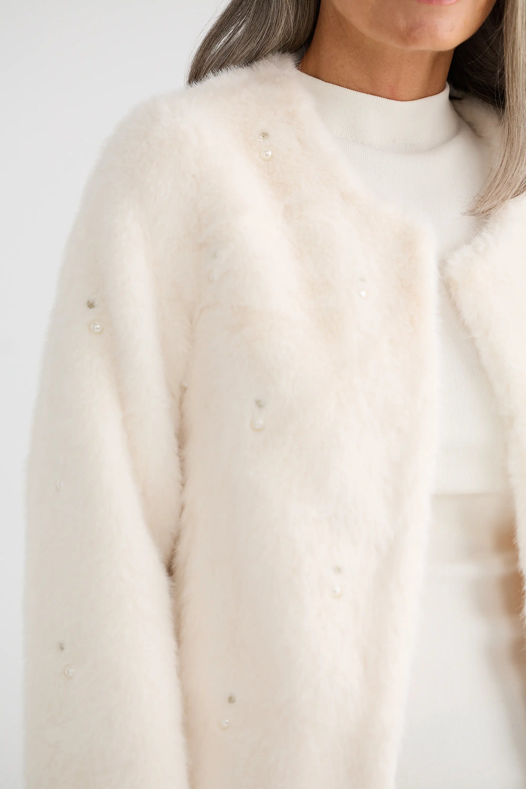 Close-up of a person wearing a cream-colored sweater against a white background