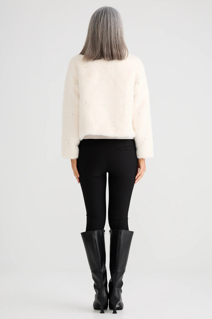 Person wearing a white sweater, black pants, and black boots on a white background