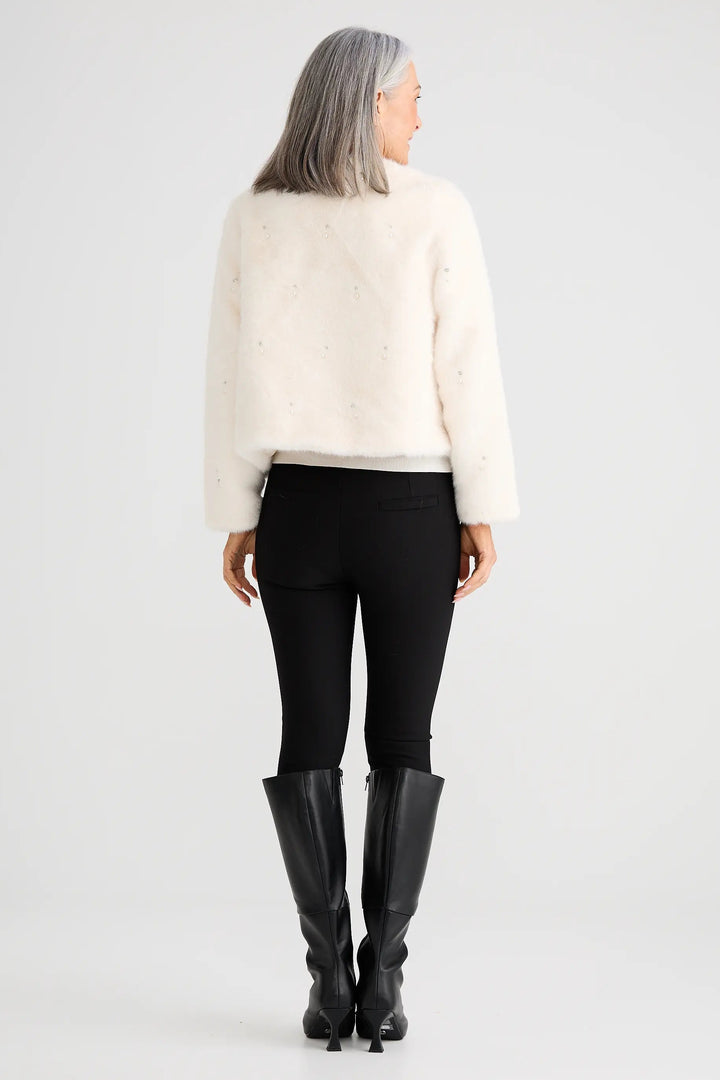 Person wearing a white sweater, black pants, and black boots on a white background