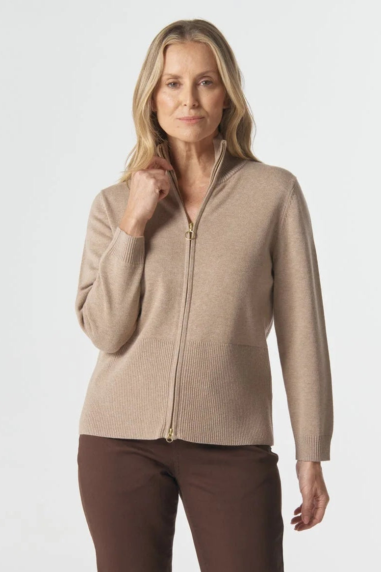 Woman wearing a beige zip-up jacket and brown pants on a white background