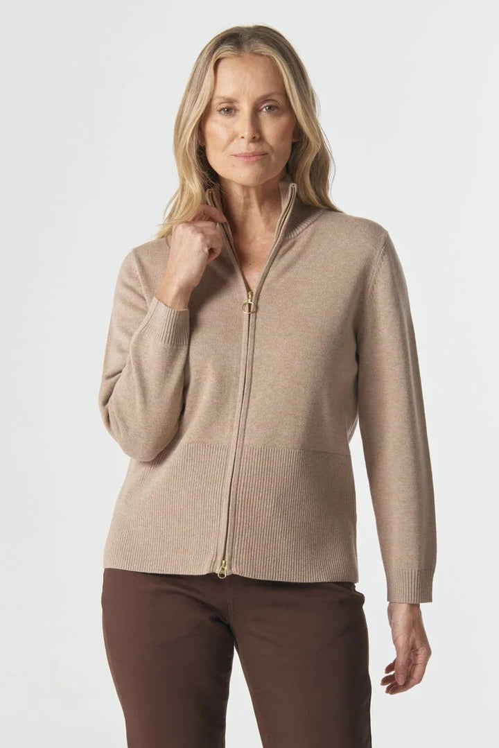 Woman wearing a beige zip-up jacket and brown pants on a white background