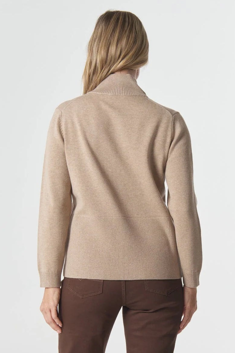Woman wearing a beige sweater and brown pants on a white background