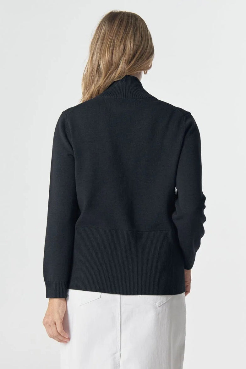 Person wearing a navy cardigan and white pants on a white background