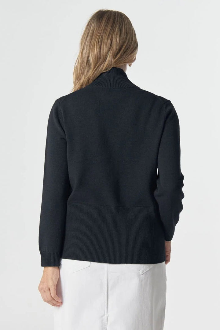 Person wearing a navy cardigan and white pants on a white background
