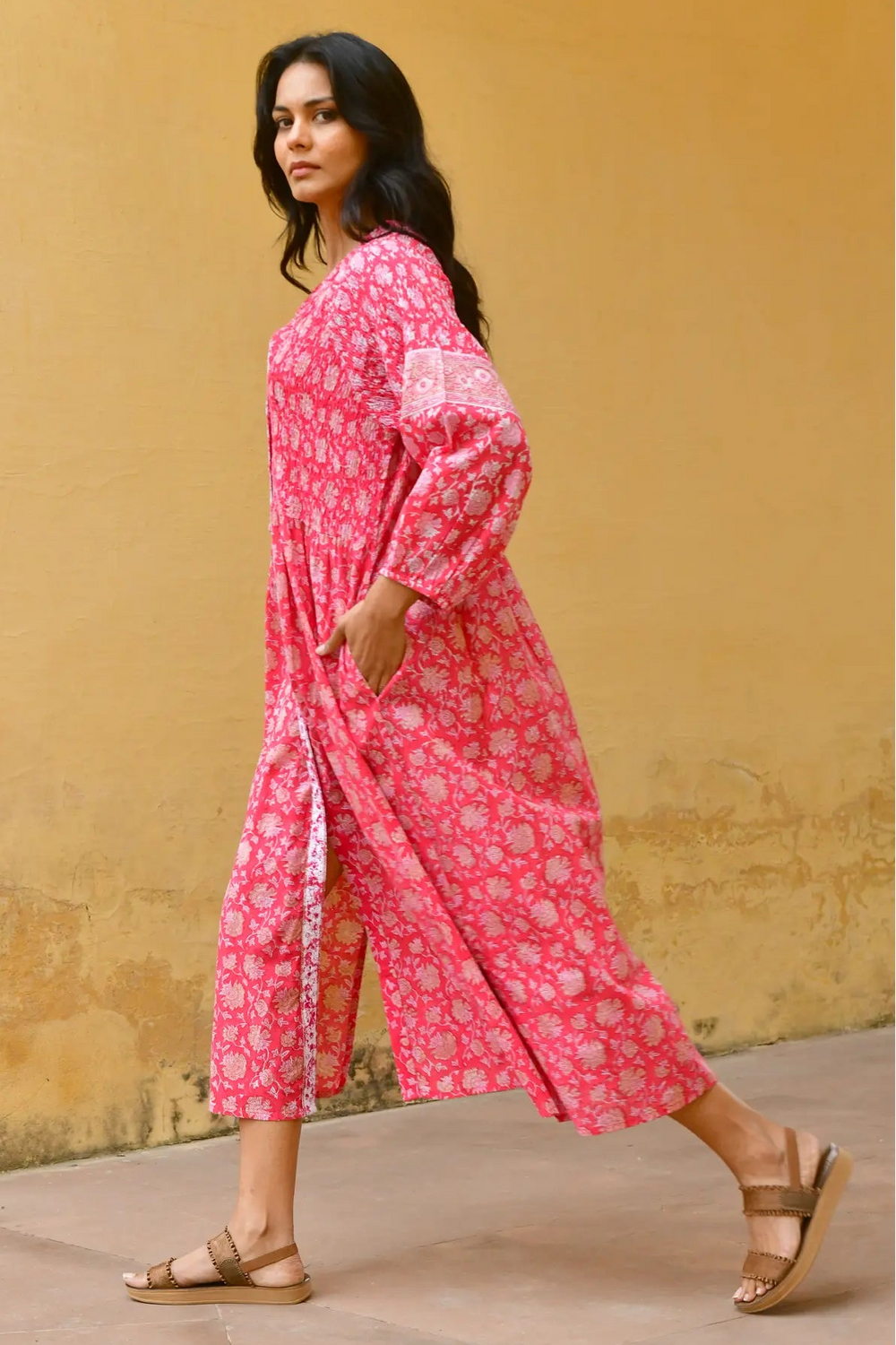 Woman wearing a pink floral dress against a yellow wall - Azure & Indigo Camillia Maxi Dress Cherry.
