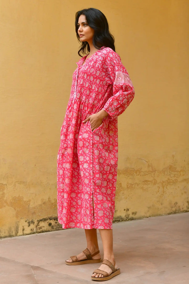 Woman wearing a pink floral dress against a yellow wall. Azure & Indigo Camillia Maxi Dress Cherry