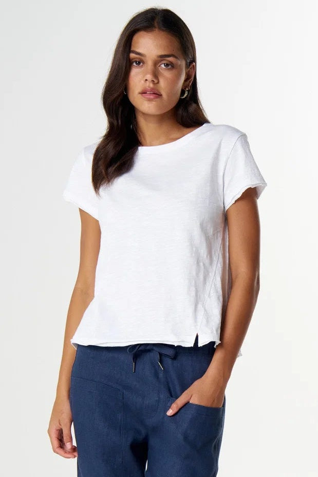 A woman modeling a white short-sleeve t-shirt and navy blue cropped pants with a drawstring waist, paired with brown sandals, against a plain white studio background.