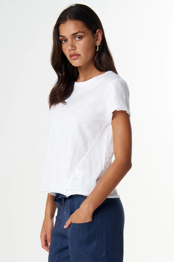 A woman modeling a white short-sleeve t-shirt and navy blue cropped wide-leg pants, paired with black flip-flop sandals, against a clean white studio background.