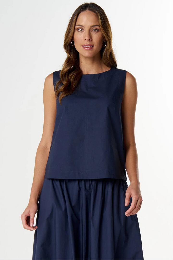 A woman modeling a sleeveless navy blue top and matching pleated skirt against a clean white studio background.
