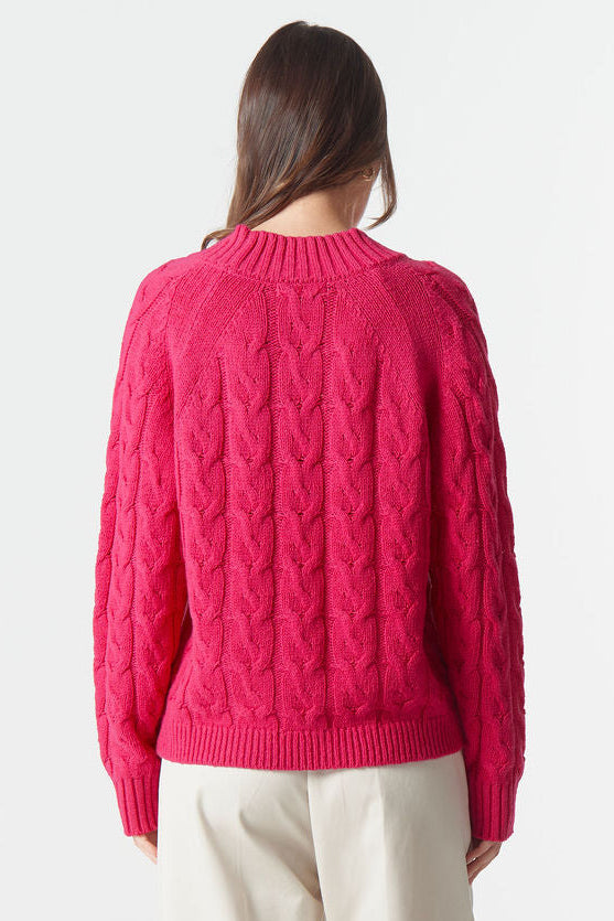 Person wearing a bright pink sweater and beige pants on a white background