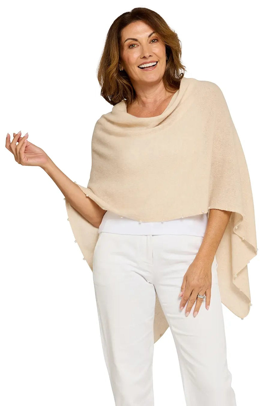 Woman wearing a beige poncho and white pants on a white background